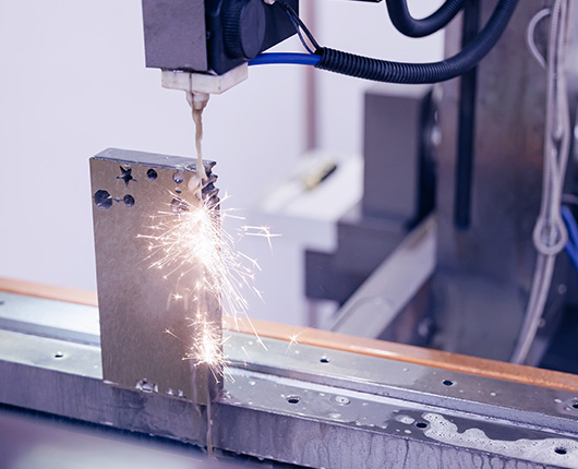 Une pièce carré dans l'atelier de Mérault dans l'Oise qui est travaillée par électroérosion service proposé par l'entreprise Mérault.